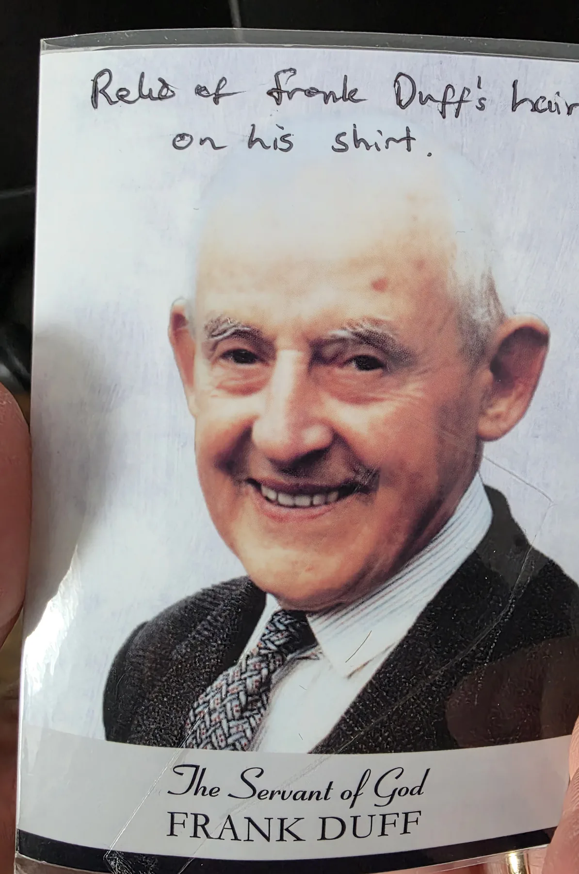 A laminated holy card of the Servant of God Frank Duff, inscribed by hand &lsquo;Relic of Frank Duff&rsquo;s hair on his shirt&rsquo;