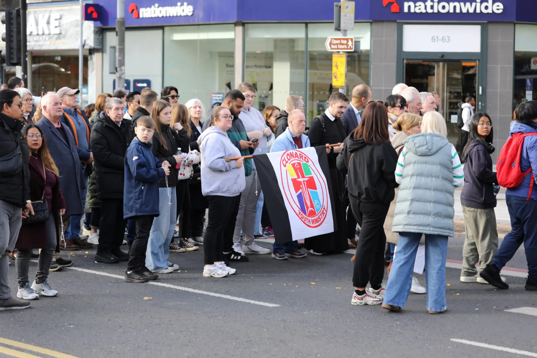 Walkers gathered at a city-centre junction, praying together around a banner