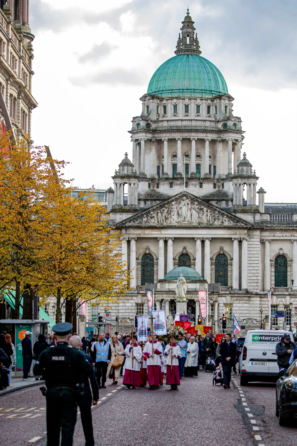 The dome of Belfast City Hall above the procession, with a police officer watching over the route