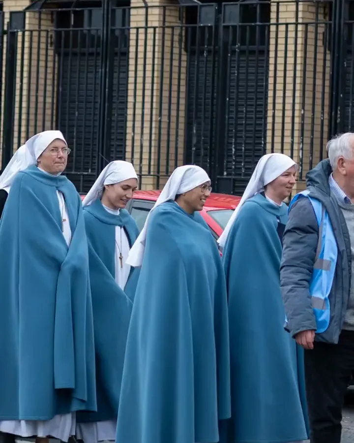 Four Sisters in blue cloaks and white veils walking in the procession.